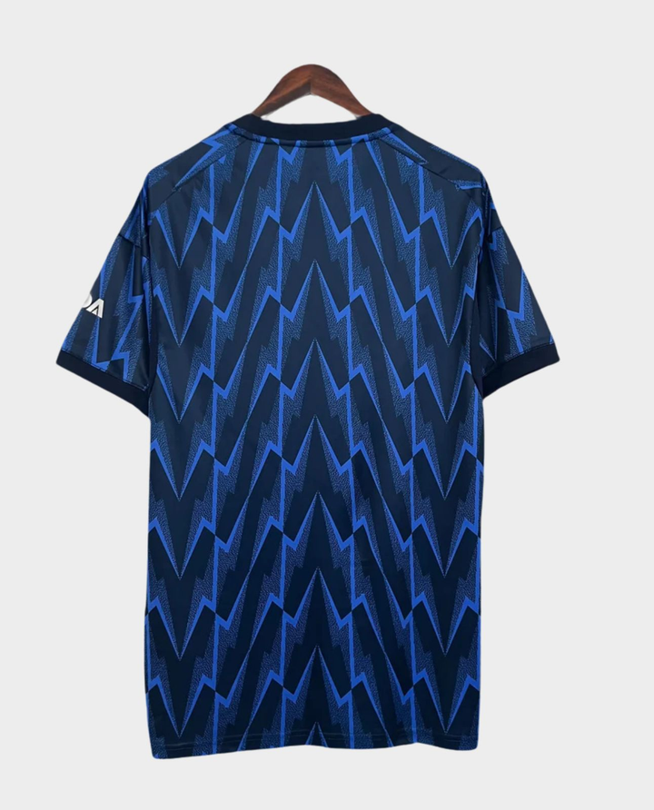 Striker Store Arsenal away jersey 2025-26 navy blue back view with electric zigzag pattern on hanger
