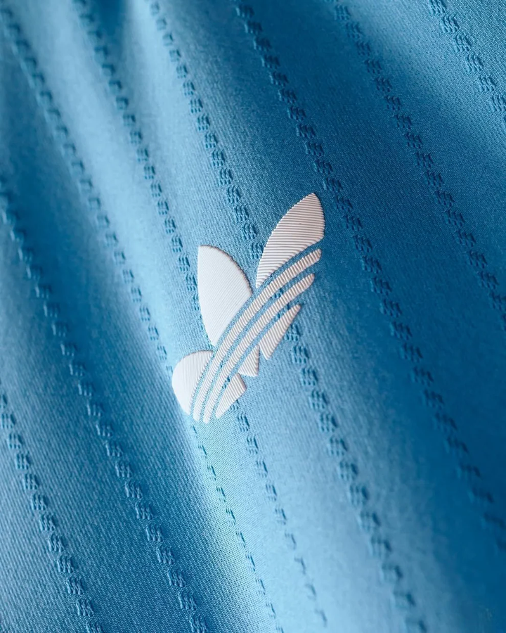 Striker Store close up of light blue textured fabric and white trefoil logo on Inter Miami 2025-26 Third Jersey