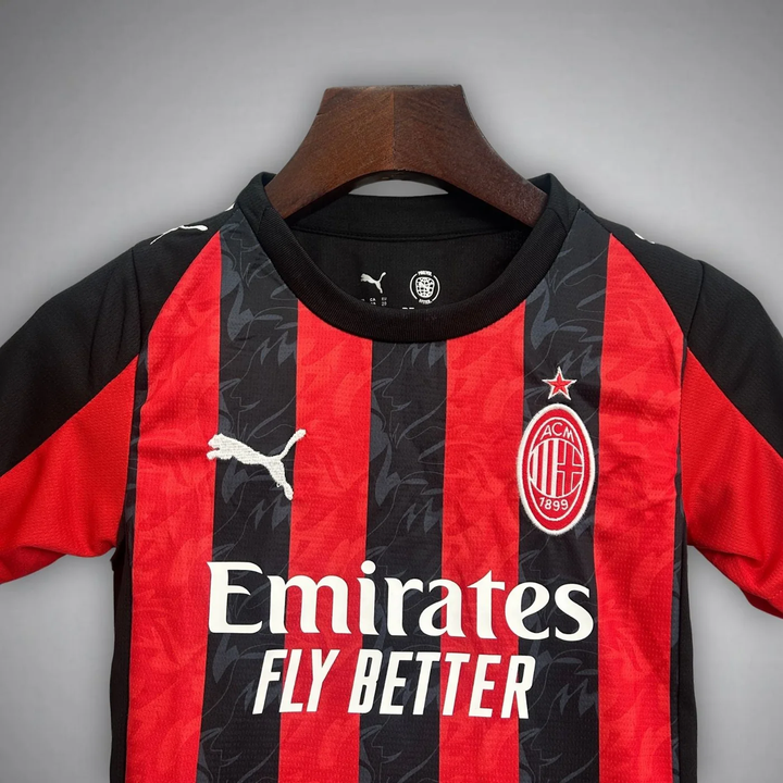 Kids AC Milan home kit 2025-26 featuring black and red stripes with Puma branding