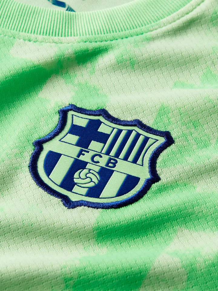 Close-up of Kids Barcelona Jersey 2024-25 featuring the iconic club crest on a green background