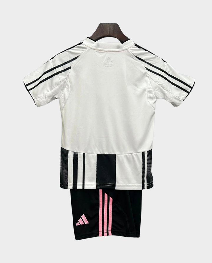 Kids Juventus home kit 2025 featuring a white jersey and black shorts with pink stripes