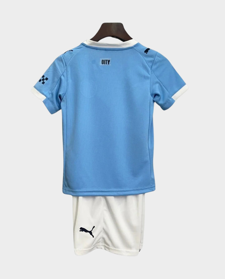 Kids Manchester City home kit 2025 featuring a light blue jersey and white shorts, perfect for young fans