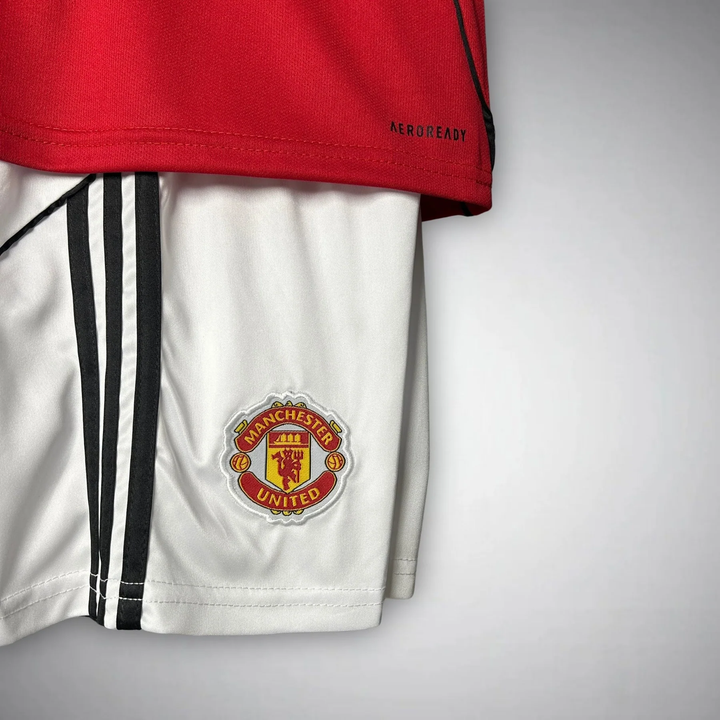 Kids Manchester United 2025-26 home kit featuring red jersey and white shorts with logo