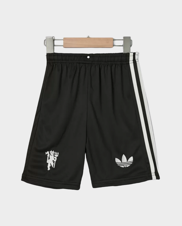 Kids Manchester United jersey 2024 set featuring black shorts with iconic logos