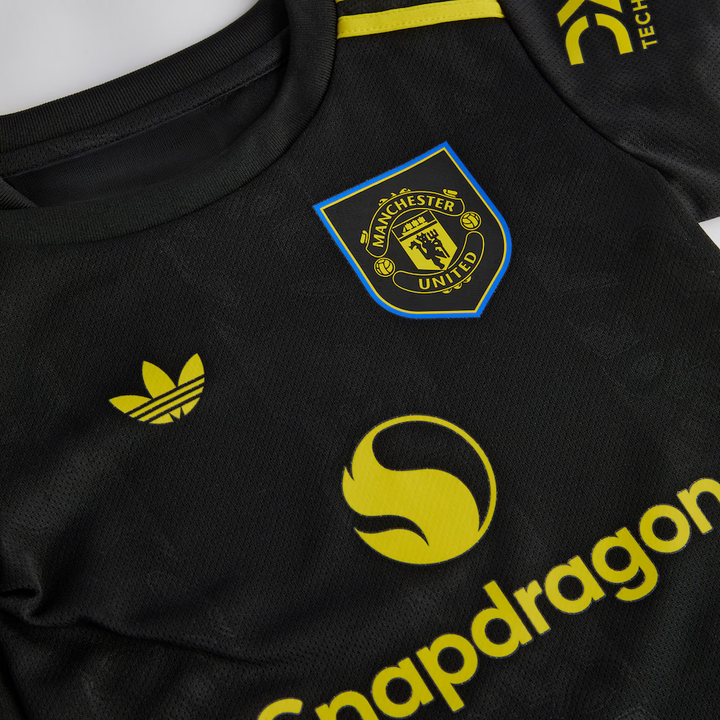 Kids Manchester United third kit 2025-26 featuring a black jersey with yellow accents and official logos