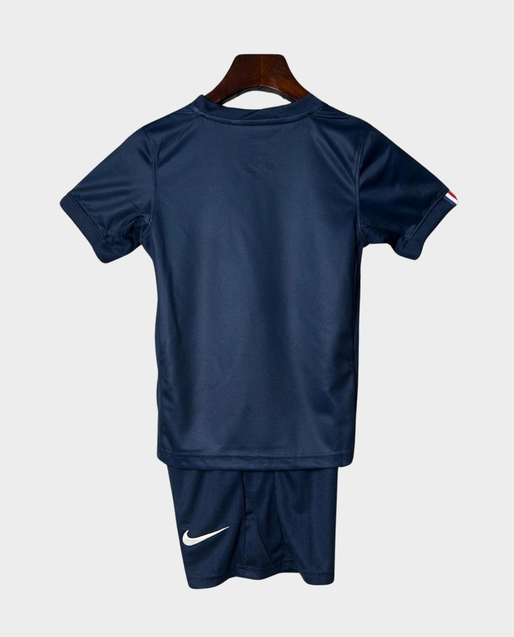 Kids PSG home kit 2025-26 featuring a navy blue shirt and shorts by Striker Store